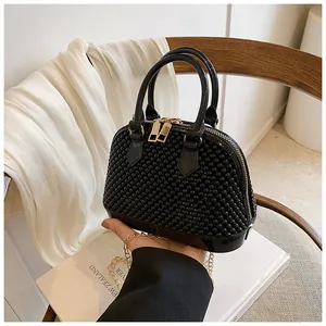 Detail of black shell-shaped jelly bag with studded texture and gold chain strap