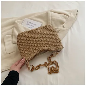 Detalle de bolso bandolera de paja con cadena de acrílico ámbar y textura tejida
