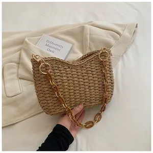 Detalle de bolso bandolera de paja tejida con cadena de acrílico color ámbar