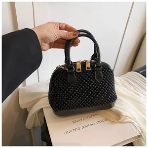 Detail of black beaded shell handbag with golden double zippers and dual handles