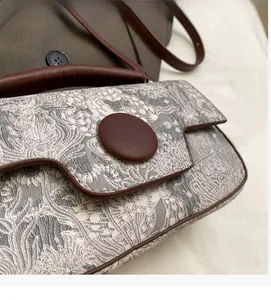 Close-up of beige jacquard fabric texture and brown leather trim on the shoulder bag