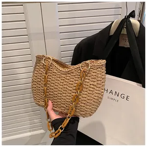 Detalle de bolso bandolera de paja tejida con cadena de acrílico ámbar y eslabones dorados
