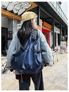 Detail of navy blue nylon crossbody bag with tactical elastic cords and buckles