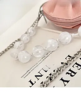 Detail showing pink pleated cloud bag with pearl bead handle and silver chain strap