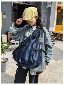 Outdoor shot of a navy blue large capacity crossbody bag with buckle details and tactical cords