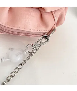 Detail of pink pleated bag featuring a durable metal chain strap and white decorative beads