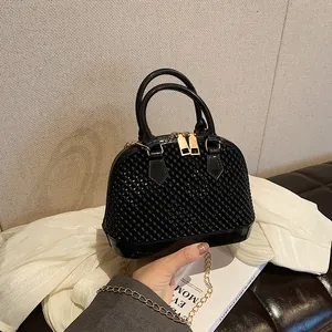 Black jelly shell bag with pearl texture, top handles and gold chain strap in life scene