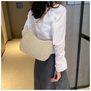 Detalle de bolso de paja trenzada con cadena de resina ámbar y hebilla metalizada