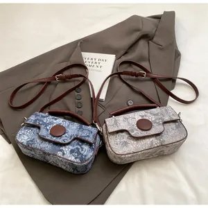 Detailed view of vintage patterned crossbody bags with brown leather handles on a grey suit