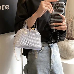 Chic transparent jelly shell bag with chain strap and gold hardware on stylish model