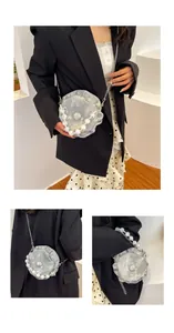 Detail of silver shell-shaped shoulder bag with pearl handle and metal chain strap