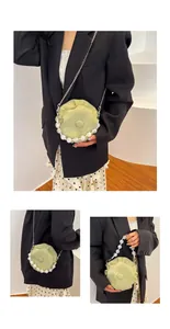 Detail of light green ruched round bag with clear bead handle and metal chain strap