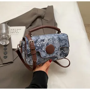 Detail view of floral print fabric with brown leather handles and silver metal hardware