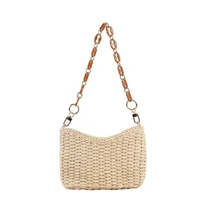 Detalle de bolso de paja tejido a mano con cadena de acrílico marrón y aros metálicos dorados