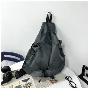 Detail of dark grey crossbody bag with adjustable elastic cords and industrial buckles