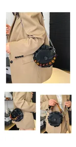 Detail of black pleated cloud round bag with amber bead handle and silver chain strap