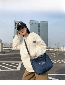 Blue denim crossbody bag detail on model 165cm height in modern urban outdoor setting