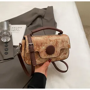 Detailed view of vintage jacquard handbag with brown leather strap on white fabric
