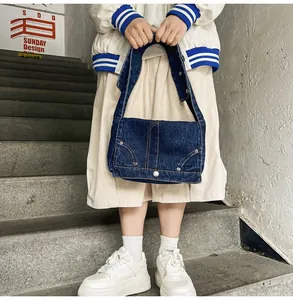 Gros plan détaillé d'un sac bandoulière en denim bleu foncé avec coutures orange