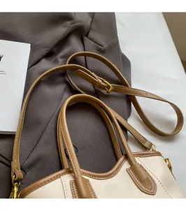 Detail showing contrast color trim and smooth adjustable long shoulder strap on bucket bag
