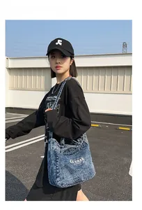 Outdoor street style shot of a model wearing a large dark blue washed denim tote bag