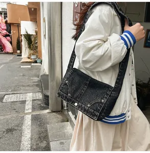 Vue détaillée d'un sac bandoulière en denim noir vintage avec surpiqûres et rivets