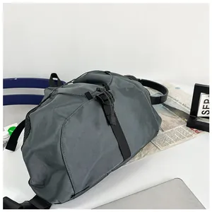 Detail of grey crossbody bag showing adjustable buckle, drawstrings and mesh back panel