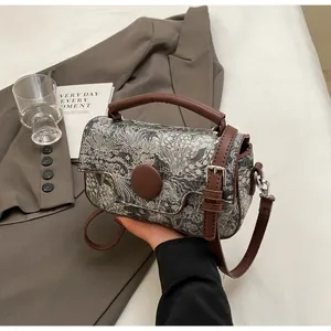 Detail of floral woven mini handbag featuring brown leather handle and round buckle