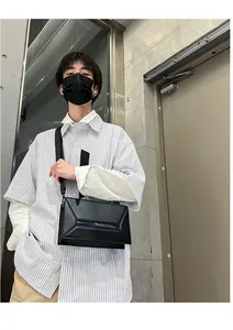 Detailed street style view of a black geometric crossbody bag with sleek 3D panels
