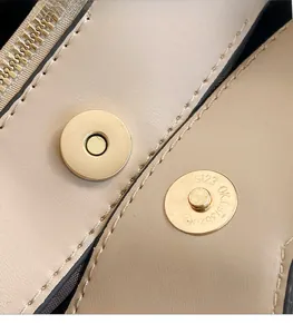 Dettaglio macro delle fibbie magnetiche dorate e trama della pelle sulla borsa
