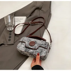 Detail of floral rectangular crossbody bag with brown leather strap and circular buckle