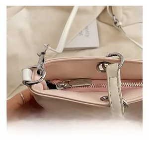Detail of silver zipper hardware and brand logo on a pink and white tote bag