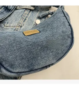 Détail du tissu denim bleu clair avec étiquette en cuir marron et bouton métallique