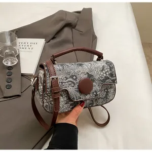 Detail of floral pattern handbag with brown leather trim and retro clasp on grey suit