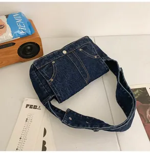 Détail du sac bandoulière en denim bleu foncé avec poches style jean et boutons en métal