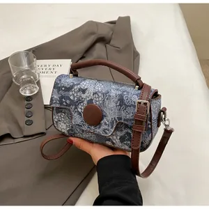 Detail of blue and white vintage floral fabric texture with brown leather trim on a handbag