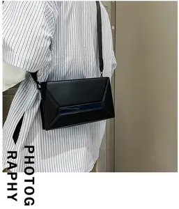 Detailed view of black geometric crossbody bag with 3D panels and blue stripe detail