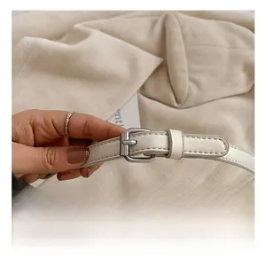 Close-up of adjustable white leather shoulder strap with silver metal buckle on tote bag