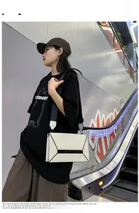 Detail of white rectangular crossbody bag with black geometric pattern and wide strap