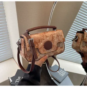 Close-up of vintage embossed pattern and leather handle on brown crossbody bag