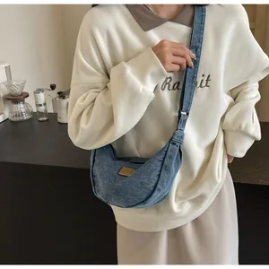 Gros plan du sac croissant en denim bleu avec sangle réglable et détail de patch