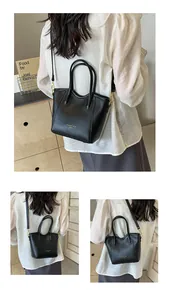 Detail view of the black leather tote bag featuring gold hardware and adjustable strap