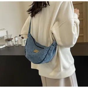 Vue latérale d'un sac bandoulière en denim bleu porté par un mannequin dans un café