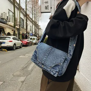 Sac bandoulière en denim bleu classique avec rivets vintage porté par un mannequin en ville