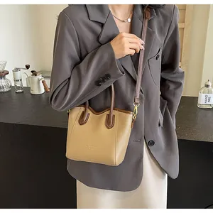 Detail of a beige and brown contrast tote bag with adjustable strap and carry handles