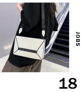 Detail of geometric box crossbody bag featuring contrast piping and adjustable strap