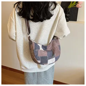 Detail view of the patchwork canvas crescent bag worn over the shoulder by a model
