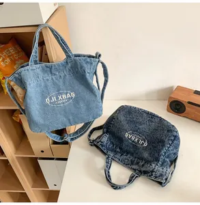 Detailed view of light and dark blue denim tote bags with brand lettering and strap