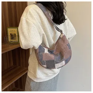Detail of a patchwork canvas shoulder bag featuring brown, navy and beige color blocks