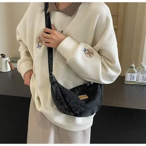 Détail du sac croissant en denim foncé avec fermeture éclair et étiquette de marque